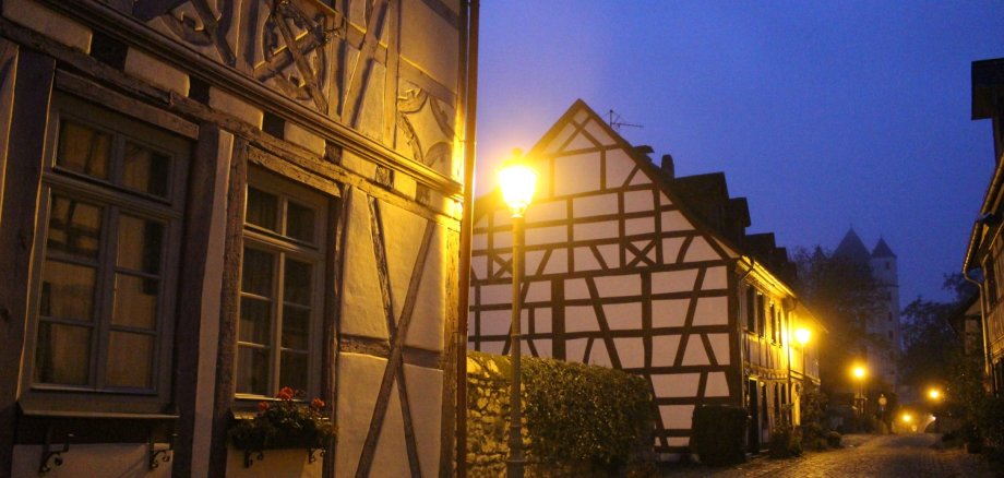 Fachwerkhäuser in der Burgstraße leuchten durch Straßenlaternen bei Nacht