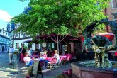 Der Eltviller Marktplatz ist ein beliebter Treffpunkt. Menschen sitzen unter Sonnenschirmen neben einem Brunnen auf dem Eltviller Marktplatz.
