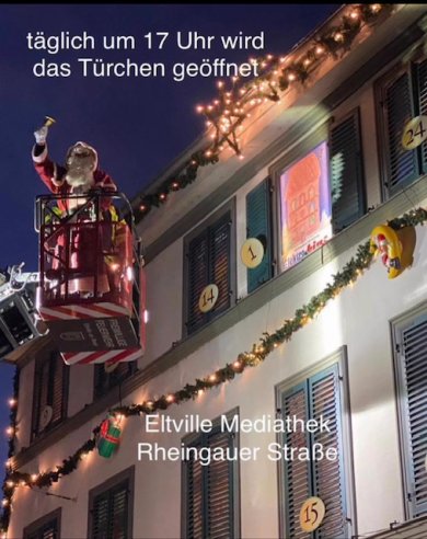 Ein Weihnachtsmann in einem Hubwagen vor einer weihnachtlich geschmückten Häuserfassade