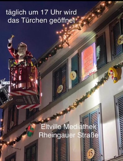 Ein Weihnachtsmann in einem Hubwagen vor einer weihnachtlich geschmückten Häuserfassade