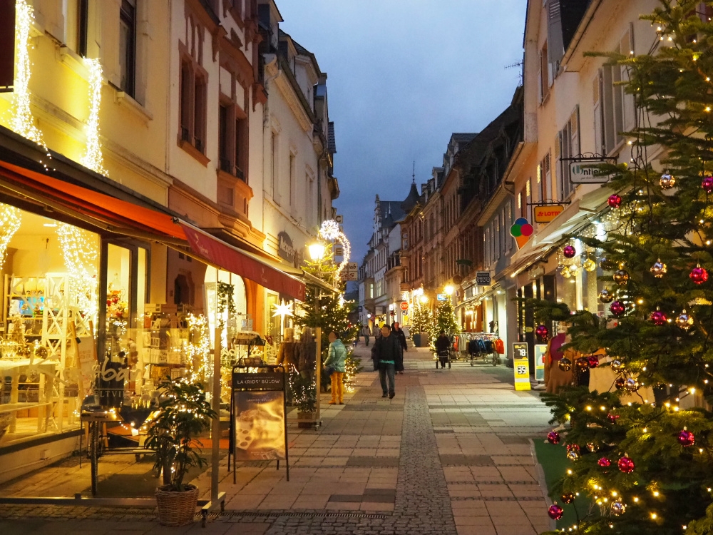 Beleuchtete Fußgängerzone mit Tannenbäumen und Lichtern zur Weihnachtszeit