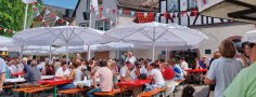 Das Erdbeerfest ist immer wieder ein Besuchermagnet. Viele Besucher sitzen auf Bierzeltgarnituren unter Sonnenschirmen auf dem Erbacher Marktplatz.