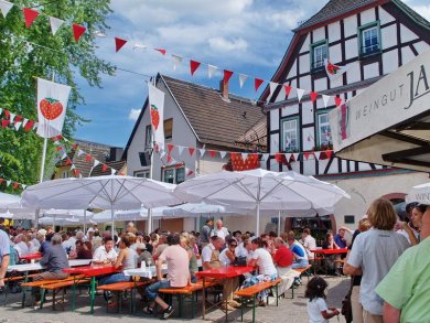 Viele Besucher sitzen auf Bierzeltgarnituren unter Sonnenschirmen auf dem Erbacher Marktplatz.
