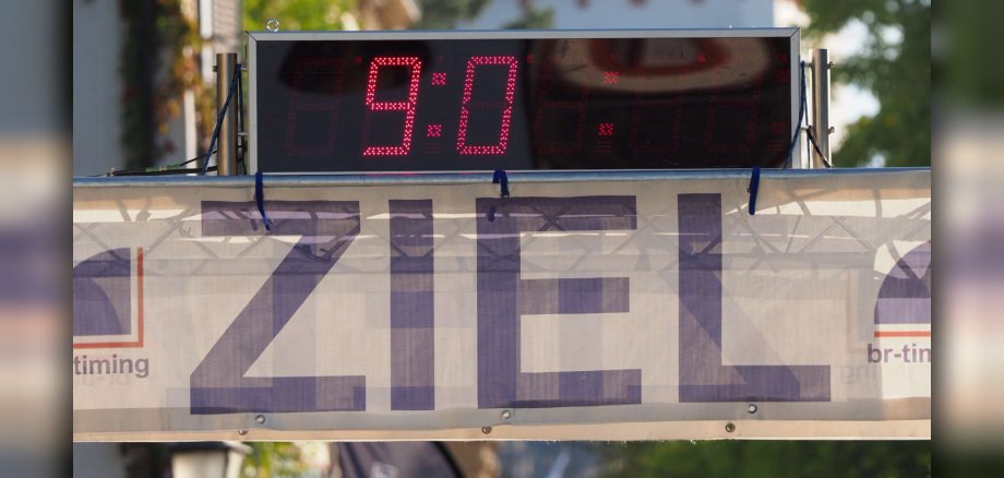 Ein Banner mit der Aufschrift "Ziel" und einer Zeitanzeige, im Hintergrund sieht man den Eltviller Burgturm.