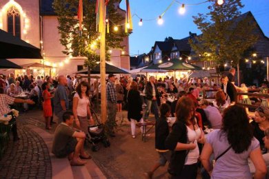 Gäste sitzen und stehen zusammen beim Kirchweihfest am Abend.