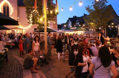 Gäste sitzen und stehen zusammen beim Kirchweihfest am Abend.