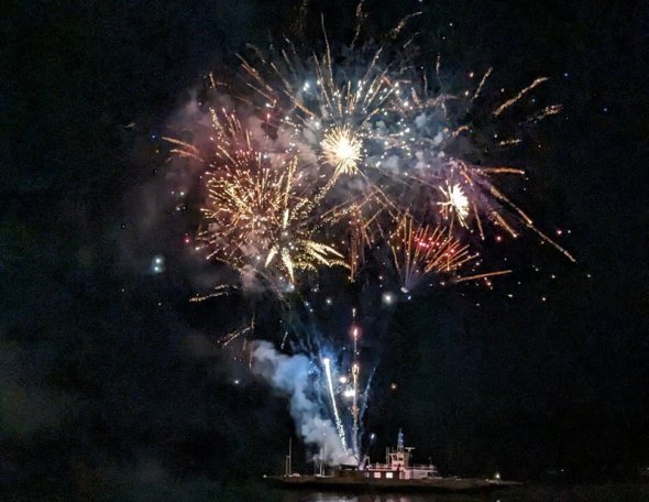 Feuerwerk, abgeschossen von einem Schiff auf dem Rhein, leuchtet bunt im Nachthimmel