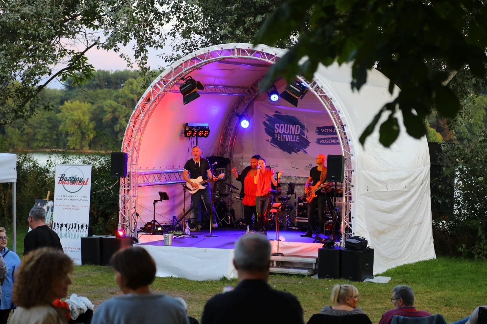 Eine Band spielt auf der Bühne im Rosenbad, während das Publikum gespannt zuhört.