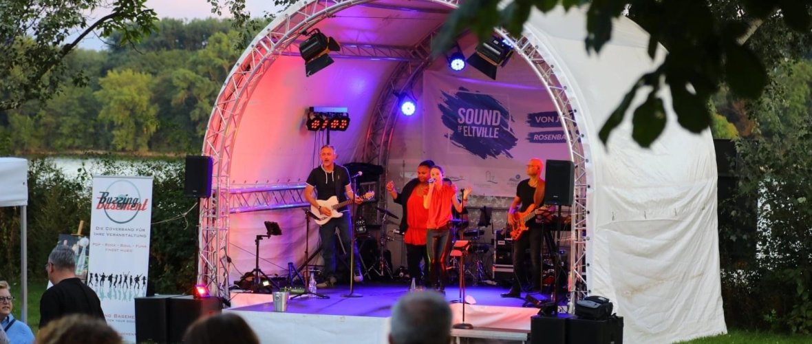 Eine Band spielt auf der Bühne im Rosenbad, während das Publikum gespannt zuhört.