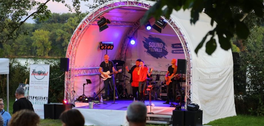 Eine Band spielt auf der Bühne im Rosenbad, während das Publikum gespannt zuhört.