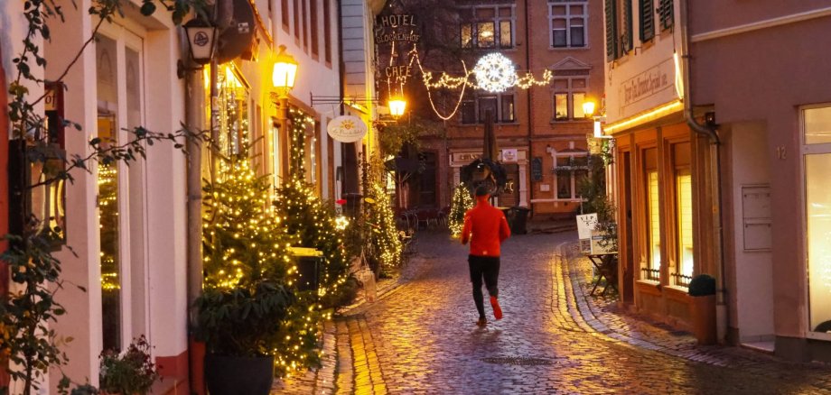 Die Eltviller Altstadtstraßen sind mit Weihnachtslichtern geschmückt, dazwischen ist ein Jogger unterwegs, den man von hinten sieht.