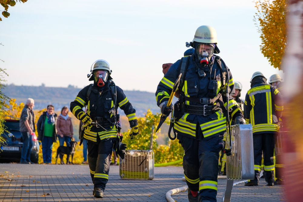 Zwei Feuerwehrleute in voller Montur mit Maske gehen auf die Kamera zu