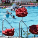 Drei rote Rosen aus Metall, im Hintergrund ist das Becken zu sehen.