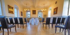 Im Burgsaal sind Trauungen mit bis zu 70 Personen möglich. Blick von hinten auf die Stuhlreihen, die seitlich angeordnet sind und die beiden Stühle für das Brautpaar in der Mitte.