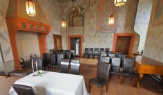 Der Grafensaal hat eine außergewöhnliche Wandbemalung aus dem 14. Jahrhundert. Bestuhlter Raum mit Wandmalerei, orangenen Verzierungen und einem Ofen.