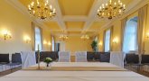 Der Kurfürsten Saal bietet ein festliches Ambiente. Foto aus Sicht der Standesbeamtin in den ERaum: Vorne stehen zwei Stühle für das Brautpaar, dahinter stehen Stuhlreihen und goldene Kronleuchter hängen von der Decke.