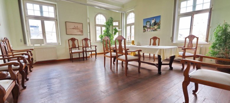 Ein Timmer mit Holzstühlen und dunkelm Holzboden, an der Wand hängt ein Bild der Eltviller Burg.
