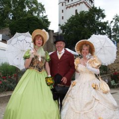 Ein Mann (mitte) und zwei Frauen haben sich in Kostümen der Biedermeierzeit gekleidet.