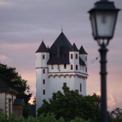 Burgturm der Kurfürstlichen Burg in der Dämmerung, rechts sieht man eine Straßenlaterne.