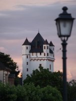Burgturm der Kurfürstlichen Burg in der Dämmerung, rechts sieht man eine Straßenlaterne.