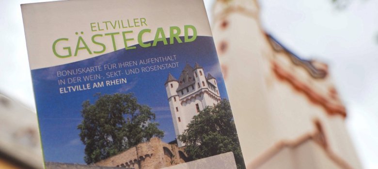 Die Eltviller GästeCard, im Hintergrund sieht man den Turm der Kurfürstlichen Burg Eltville.