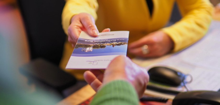 Symbolbild: Man sieht eine Hand mit einem Flyer zu Eltville, die diesen einer anderen Hand übergibt.