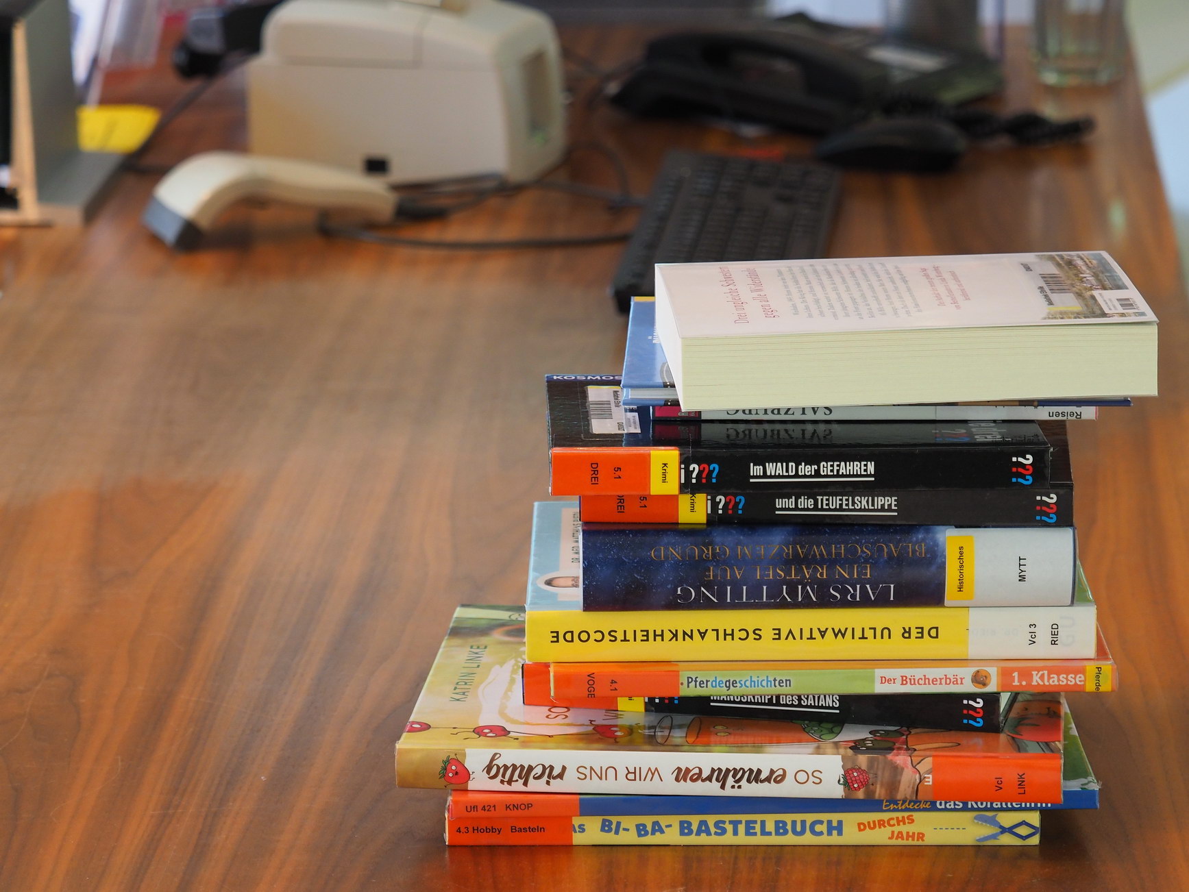 Der Bestand der Mediathek umfasst aktuell rund 16.000 Medien. Ein Stapel Bücher liegt auf einem Tisch.