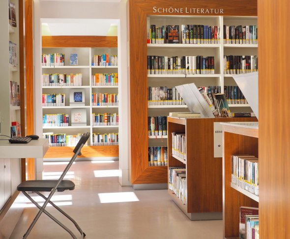 Die Mediathek verfügt über zwei öffentliche Internetplätze. An den Wänden befinden sich Regale mit Büchern, links steht ein Stuhl mit einem Tisch. Dort befindet sich ein Internetplatz.
