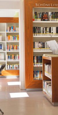 An den Wänden befinden sich Regale mit Büchern, links steht ein Stuhl mit einem Tisch. Dort befindet sich ein Internetplatz.