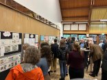 Menschen von hinten stehen an Infowänden und informieren sich