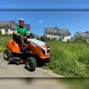 Friedhofsgärtner Matthias Bleul sitzt auf einem Rasenmäher-Traktor am Rande einer Blühwiese.