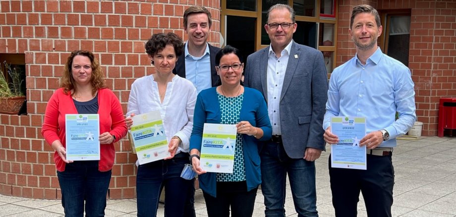 Bürgermeister Patrick Kunkel (Zweiter von rechts) und Thomas Speth (rechts) vom Amt für Soziales freuen sich mit (von links): Silvana Karsten, stellvertretende Leiterin des Wichtelhäuschens, Janina Urbinski, Leiterin der Kindergartenburg, Daniel Butschan, Elternbeiratsmitglied der Kindergartenburg und Daniela Kopp, Leiterin des Wichtelhäuschens, über das Siegel „FaireKITA“.