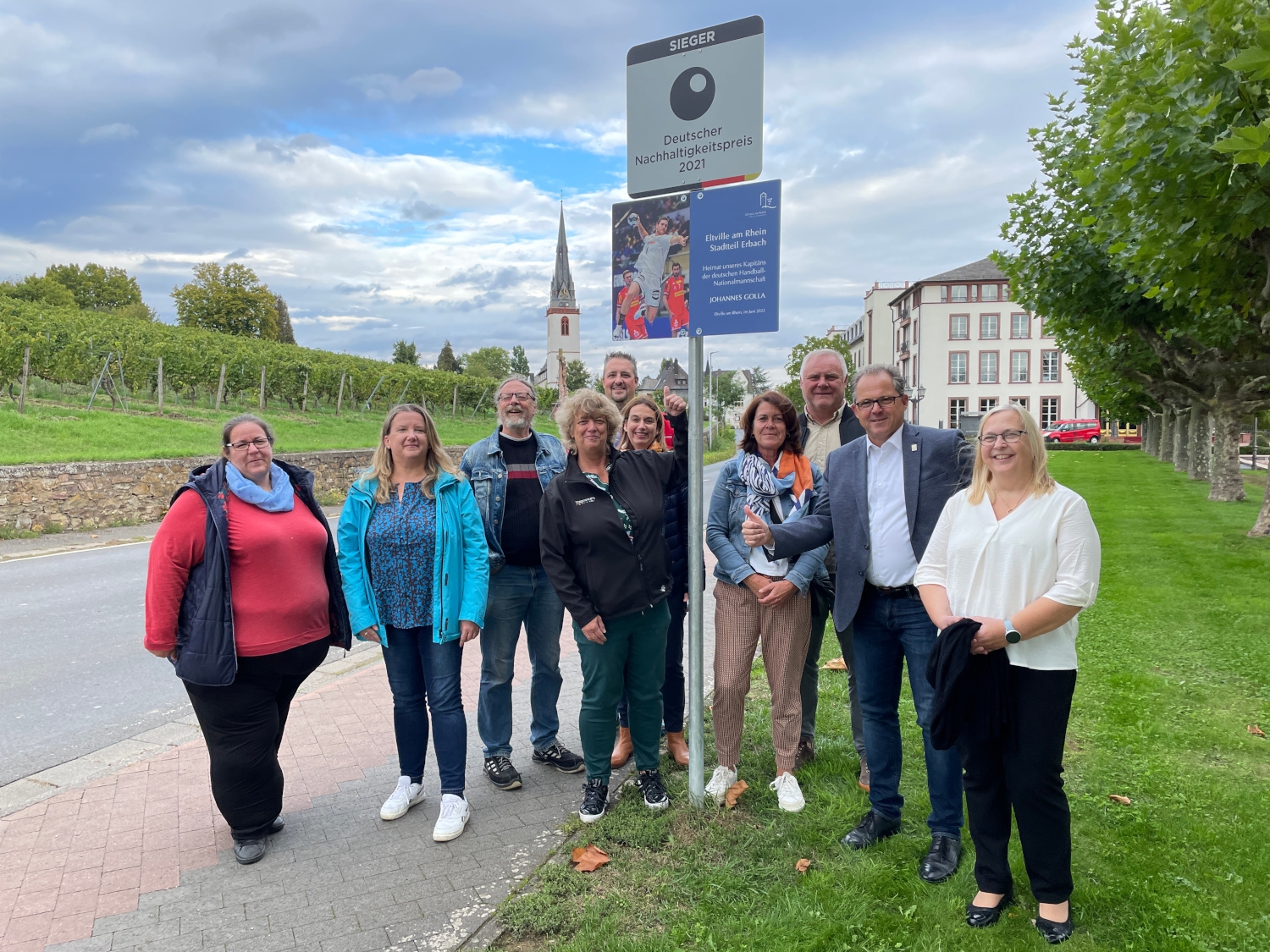 Mitglieder des Ortsbeirates stehen vor dem neu angebrachten Schild für Handballer Johannes Golla am Ortseingang von Erbach.