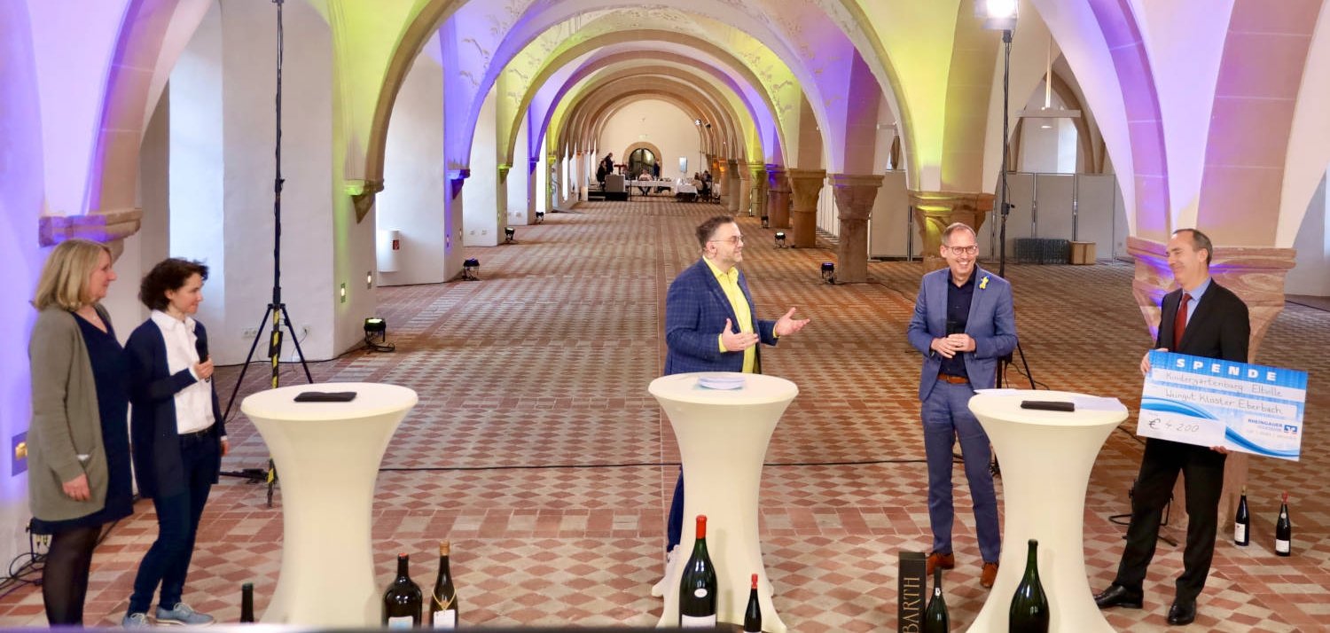 Janina Urbinski (Zweite von links) und Monika Knechtel von der Kita Kindergartenburg  und Dieter Greiner (von rechts nach links) von den Hessischen Staatsweingütern, Staatsminister Kai Klose und Fernseh- und Radiomoderator Andreas Kunze bei der Spendenübergabe in Kloster Eberbach.