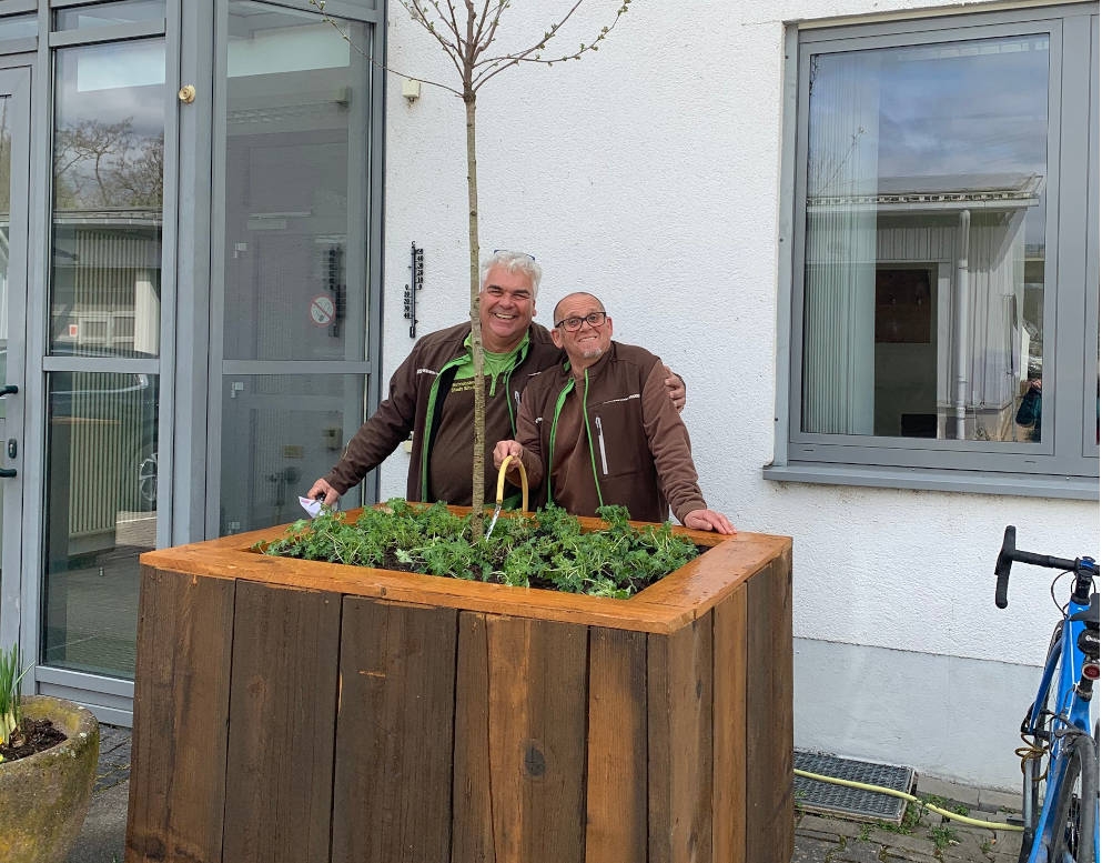 Ralph Biel (links) und Matthias Russ vom Team der Stadtwerke haben aus Müll einen Kübel für einen mobilen Baum gebaut. Ralph Biel (links) und Matthias Russ vom Team der Stadtwerke präsentieren den aus Müll selbstgebauten Kübel mit einem eingepflanzten Baum.
