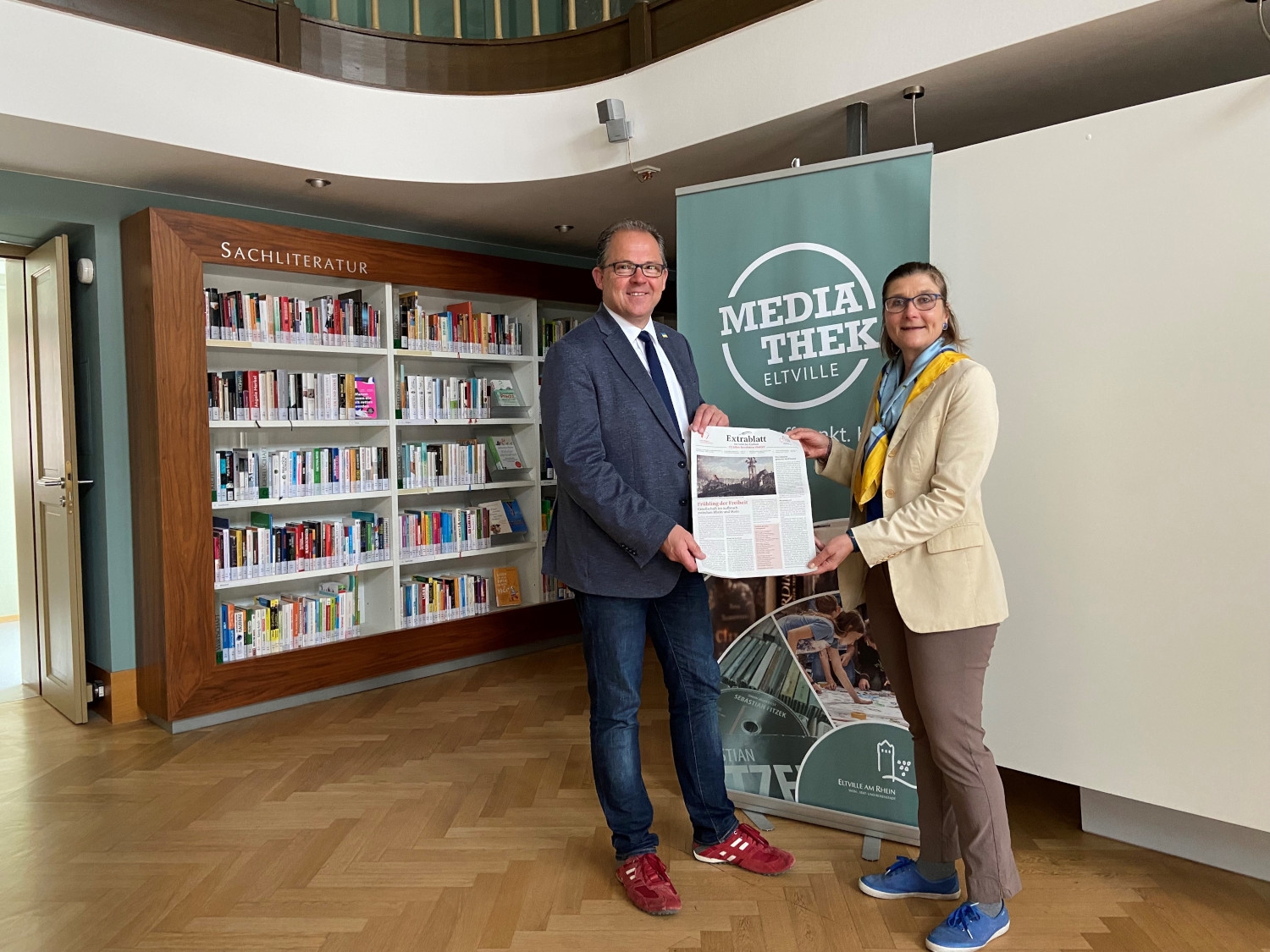 Bürgermeister Kunkel und Barbara Lilje halten das Extrablatt in der Mediathek in den Händen