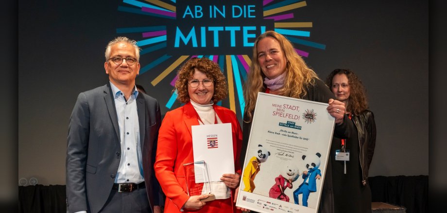 Gaby Roncarati von der Philipp Kraft Stiftung (Mitte) und Inga Olze vom Team der Stadt Eltville am Rhein nehmen den Preis beim hessischen Innenstadt-Wettbewerb „Ab in die Mitte“ aus den Händen von Wirtschaftsminister Tarek Al-Wazir entgegen.