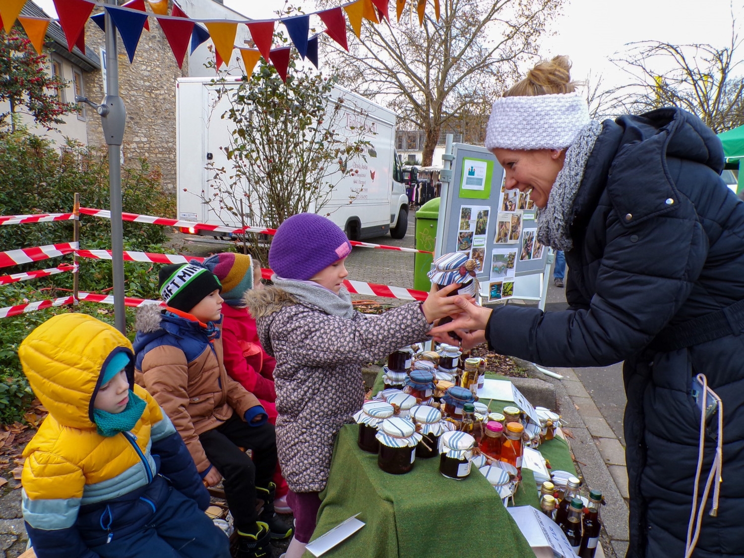 Kindergartenkinder verkaufen Marmelade an eine Frau