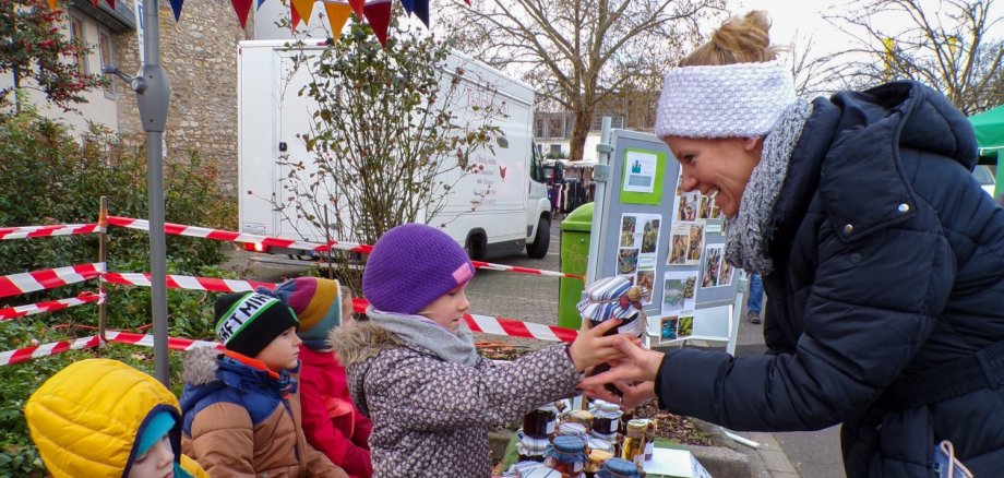 Kindergartenkinder verkaufen Marmelade an eine Frau