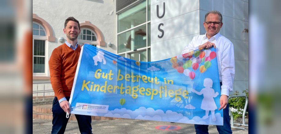 Thomas Speth und Bürgermeister Kunkel vor dem Rathaus mit der blauen Aktionsflagge in der Hand.