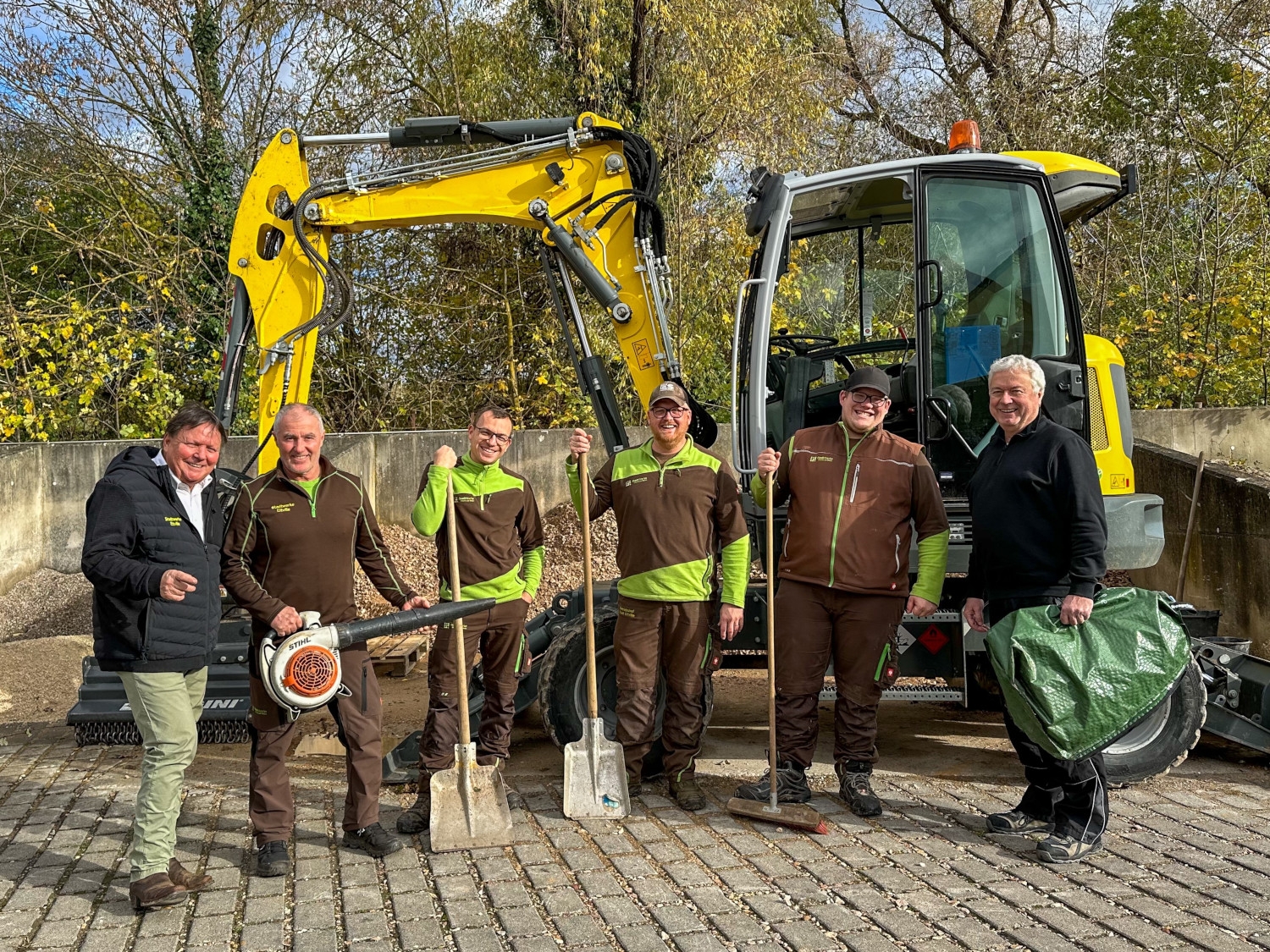 Stadtrat Andreas Panz mit Mitarbeitern der Stadtwerke vor einem Bagger