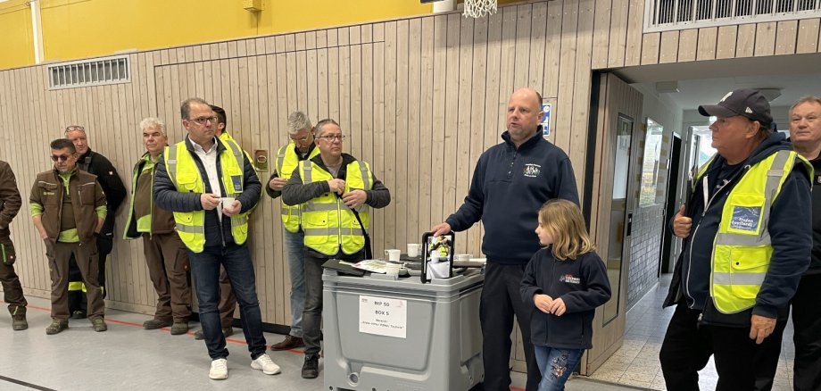 Bürgermeister und Beteiligte stehen mit Warnwesten in der Turnhalle bei der Lagebesprechung