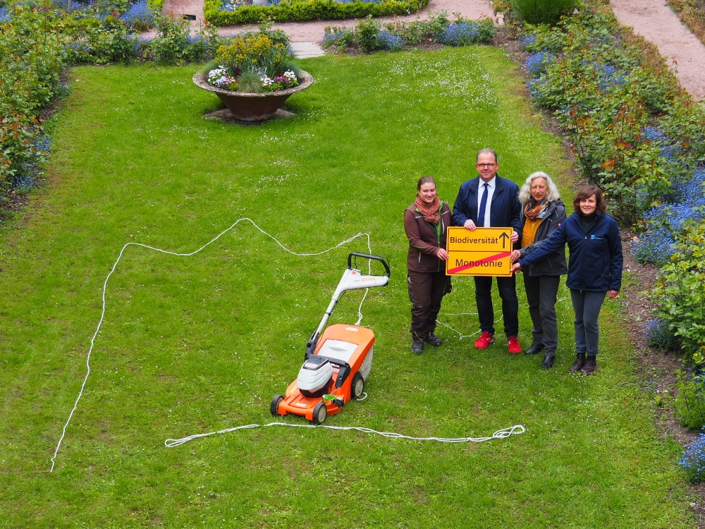 Die Beteiligten stehen auf der Rasenfläche im Rosengarten