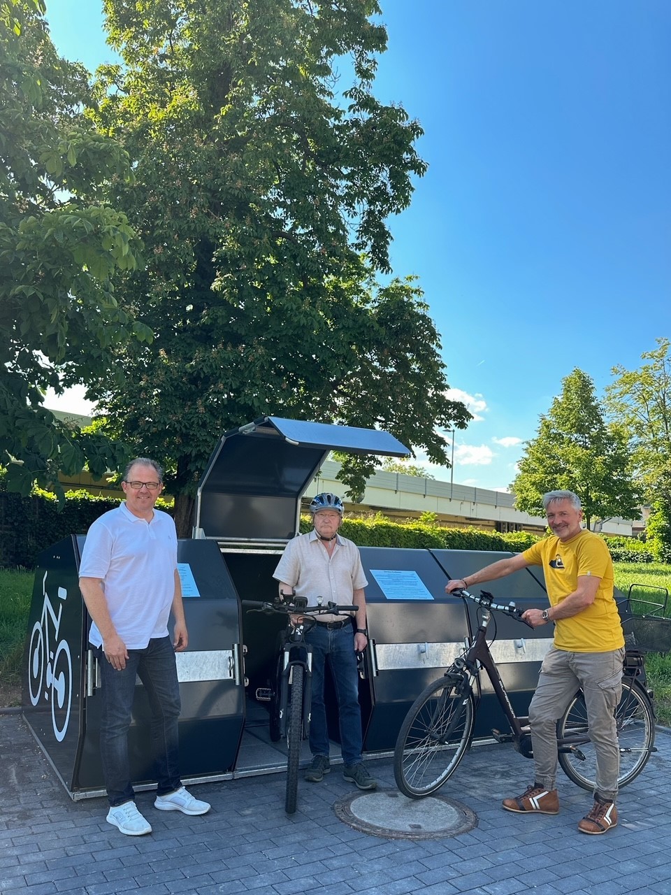 Bürgermeister, Stadtrat und Mitarbeiter der Stadt mit Rädern vor den neuen Radboxen