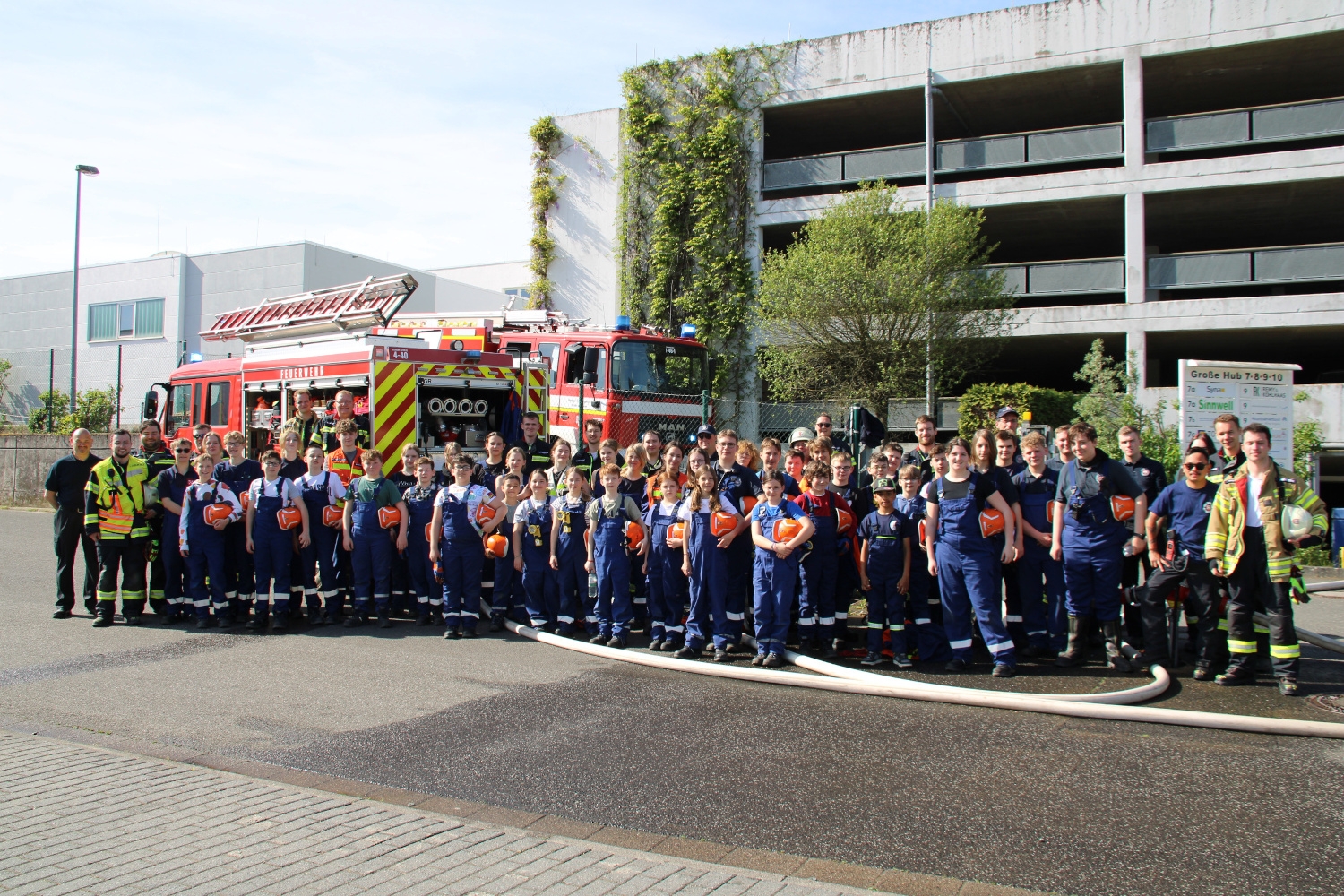 Eine Gruppe von jungen Menschen in Feuerwehruniformen, die vor einem Feuerwehrauto stehen.