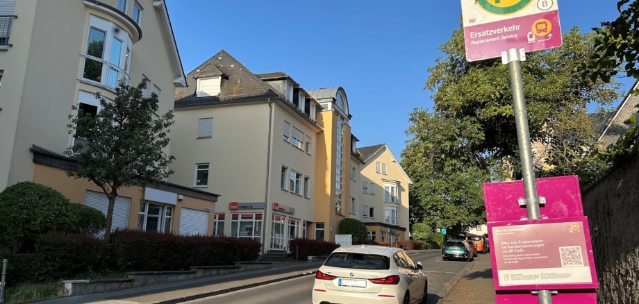 Eine Bushaltestelle an einer Straße, im Hintergrund fährt ein Auto.