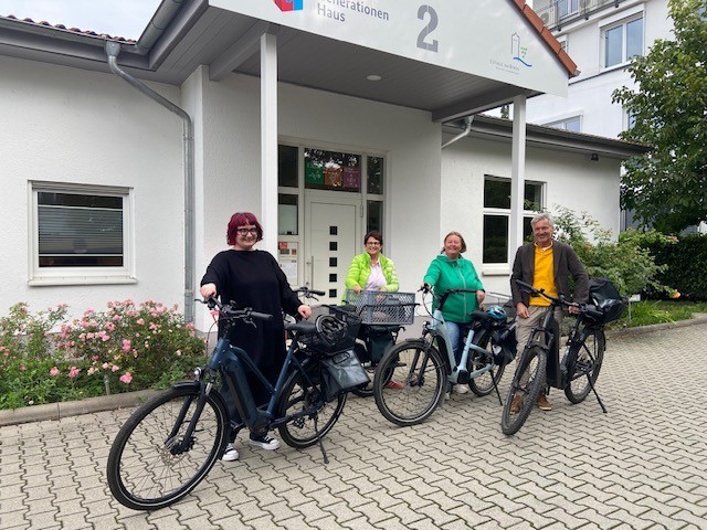 Vier Personen (3 Frauen und ein Mann) mit Fahrrädern.