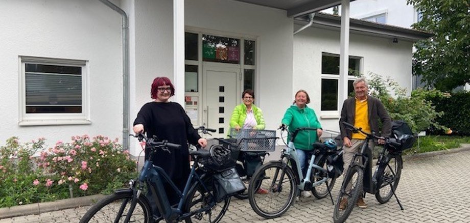 Vier Personen (3 Frauen und ein Mann) mit Fahrrädern.