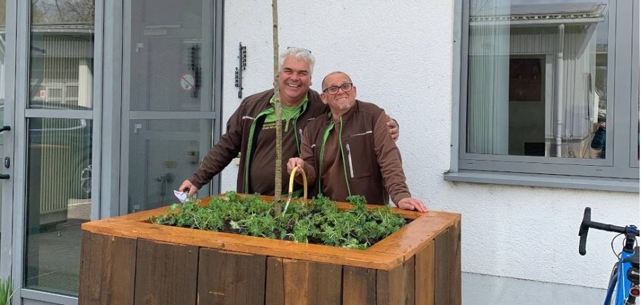 Ralph Biel (links) und Matthias Russ vom Team der Stadtwerke präsentieren den aus Müll selbstgebauten Kübel mit einem eingepflanzten Baum.