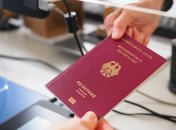 Eine Hand reicht einer anderen Hand einen Reisepass.